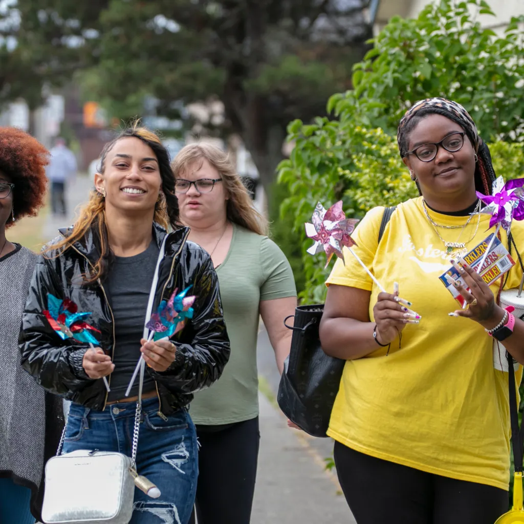 Three young people walking down the street one holding a pin wheel.