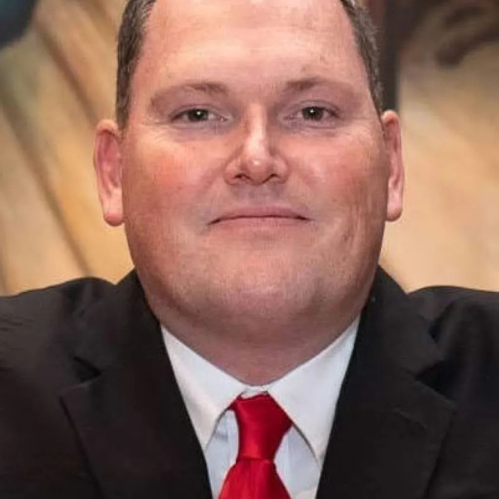 Photo of former lawmaker Rob vescovo with small smile and red tie