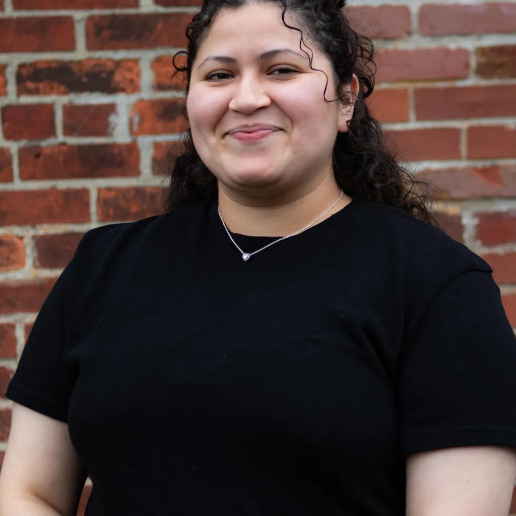 woman wearing black shirt standing against brick wall