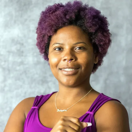 Headshot of Jasmine Solomon smiling, wearing a purple top and a nameplate necklace, with a purple natural afro and a nose ring, against a grey background.