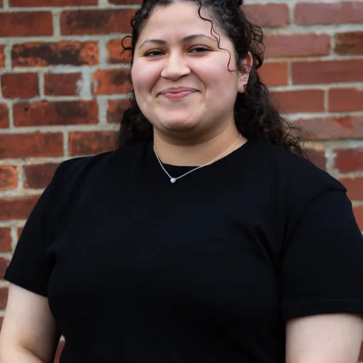 woman wearing black shirt standing against brick wall